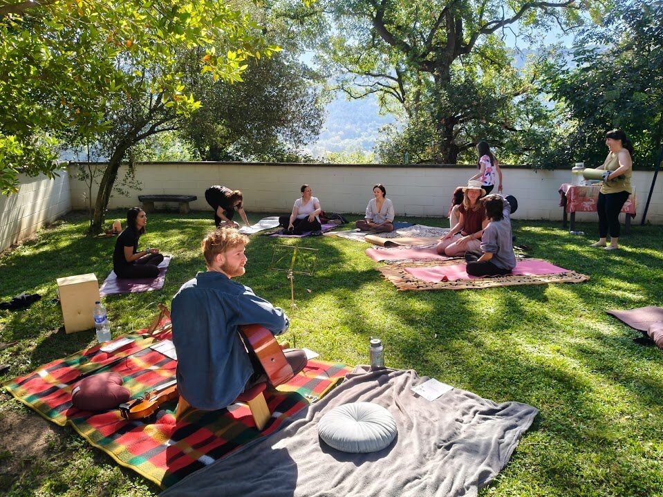 Giel leading an outdoor singing circle with guitar